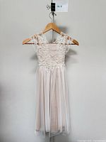 Front view of Monsoon blush lace flower girl dress on hanger