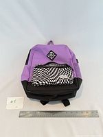 Front view showing color scheme, checkered pocket, ruler for scale