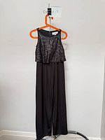 Front view of black sequin halter jumpsuit on hanger