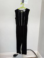 Front view of black velvet jumpsuit showing decorative trim and full length