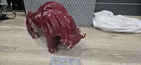 Full side view of glossy burgundy ceramic bull figurine