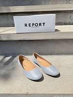 Pair of silver glitter flats in front of Report box