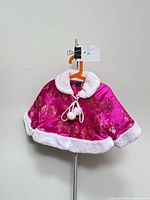 Front view of cape showing satin, embroidery, faux fur trim and pom-pom ties