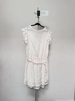 Front view of dress on hanger showing braided belt and ruffled sleeves