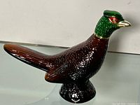 Right side view of brown glass pheasant decanter with green head cap
