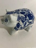 Left side view of ceramic piggy bank showing blue floral pattern and coin slot