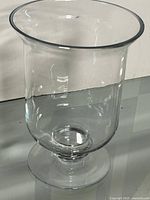 Full view of clear glass hurricane vase on pedestal base