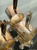 Top view of four cylindrical napkin rings showing beaded edges, footed bases, and vertical holders