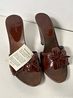 Top view of both sandals showing color, flower detail, insole markings, attached tag