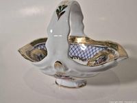 Oblique view of porcelain basket showing handle, shape and gilt trim