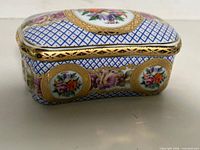 Front view of Limoges porcelain trinket box showing blue lattice pattern, floral cartouches, gold trim