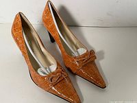 Both shoes angled showing crocodile pattern, bow detail and overall style