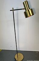 Full view of floor lamp showing brass base, black stem, brass shade