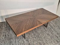Full view of rectangular coffee table showing walnut chevron top and metal base