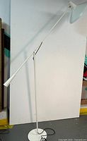 Full view of white floor lamp showing adjustable arm and base