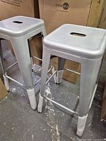 Pair of metal bar stools front three-quarter view showing overall design and finish