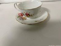 Teacup stacked on saucer showing floral design and gold trim