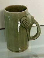 Front view of celadon mug showing body and elephant handle
