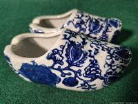 Side view of both porcelain clog shoes showing blue floral pattern