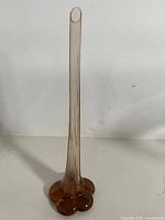 Full view of amber glass bud vase showing height and elephant foot base