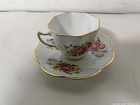 Teacup on saucer showing floral design and gold rim