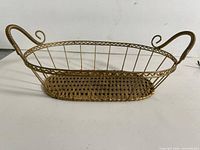 Side view of brass wire basket showing scroll handles and woven base