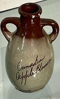 Front view of two-handled jug showing inscription and glaze