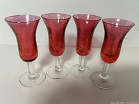Front view of four cranberry cordial glasses