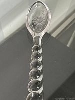 Full view of crystal salad spoon showing beaded handle and etched bowl design