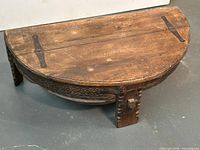 Full view of half-moon teak Chakki table showing carved skirt and iron straps