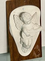 Full view of chalkware cherub on wood plaque