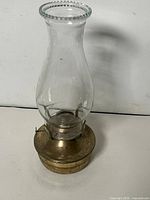 Full view of oil lamp front showing glass chimney and brass-finish base