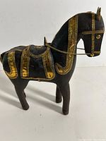 Front view of wooden horse showing brass saddle, bridle and chain reins