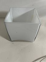 angled view of white square glass vase