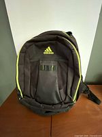 Front view of Adidas backpack showing logo, neon yellow trim, mesh front pocket