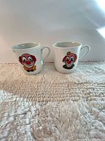 Front view of both clown face mugs