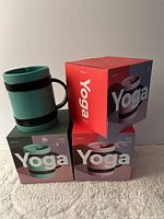 Loose ceramic travel mug atop boxed mugs