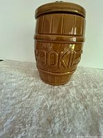 Full view of barrel-shaped brown glazed ceramic cookie jar with lid on