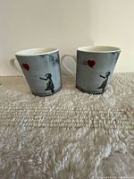 Front view of both mugs showing full Banksy design