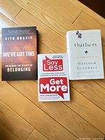 Front covers of all three paperback books on wood floor