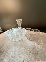 Candlestick, footed compote and additional bowls displayed on fabric surface