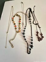 Overview of five necklaces laid out on white background
