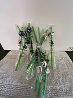 Group of sealed green plastic stirrers with various NFL helmet toppers