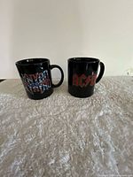 Front view of both black logo mugs