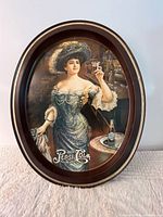 Front view of oval Pepsi-Cola metal plaque showing Art Nouveau lady graphic and rim condition