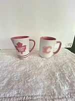 Front view of both Russ NHL mugs showing team logos and pink interiors