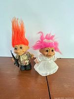 Front view of both Russ troll dolls displaying outfits, hair colors and rifle accessory