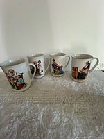 Front view of four illustrated porcelain mugs showing different scenes