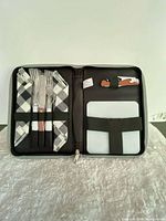 Open case showing utensils, napkins, opener, cutting board secured inside