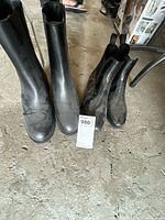 Both pairs of black Chelsea boots side by side on floor
